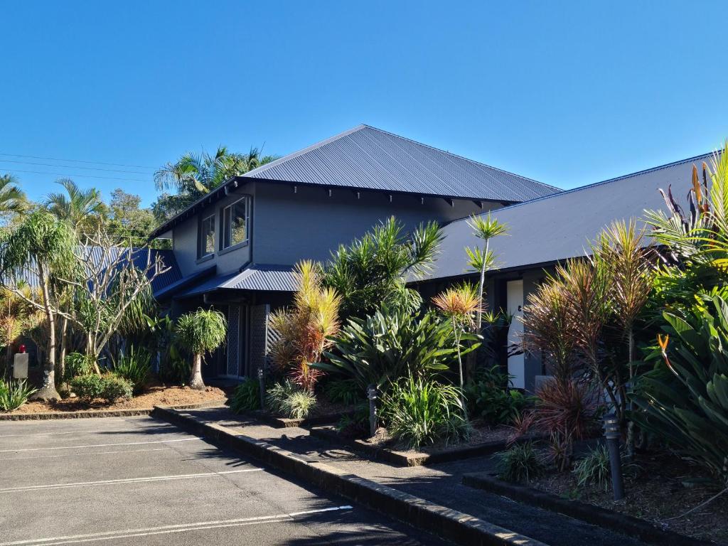 a blue house with plants in front of a street at The Park Hotel Motel, Suffolk Park in Byron Bay