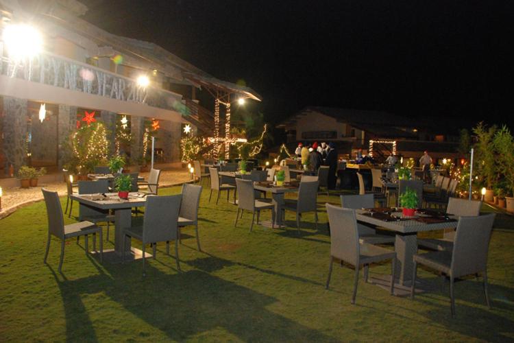 a group of tables and chairs in a yard at night at Ekaant The Retreat in Lavasa