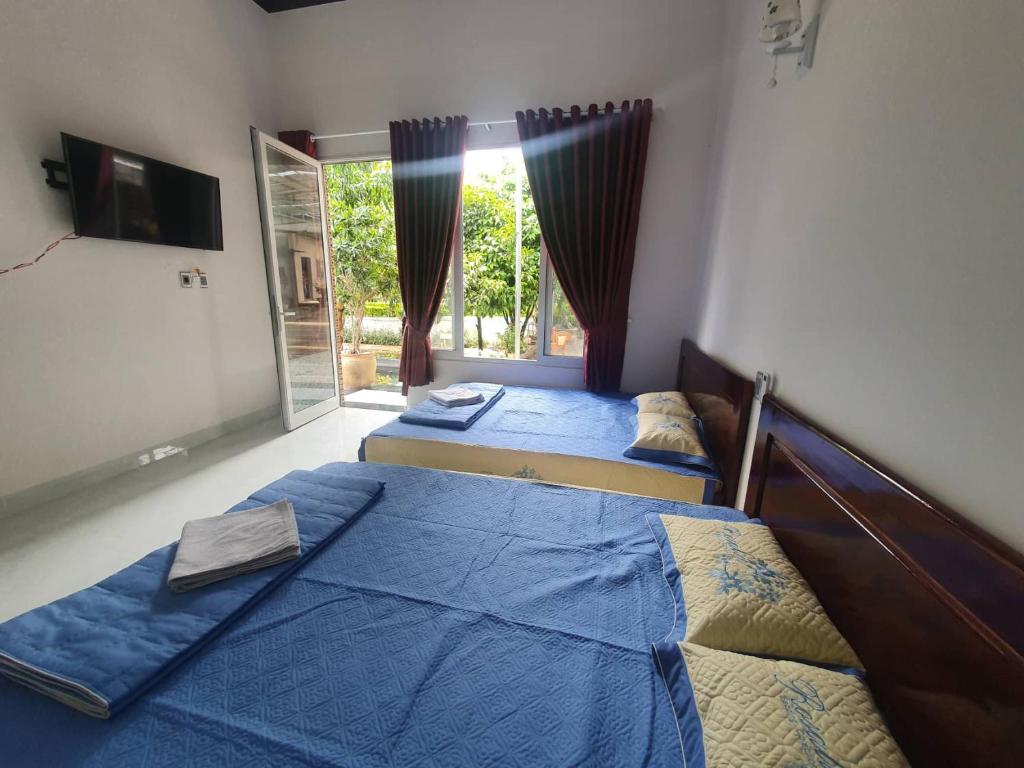 2 camas individuales en una habitación con ventana en Nhà Nghỉ THẢO NGUYÊN XANH en Buon Ma Thuot