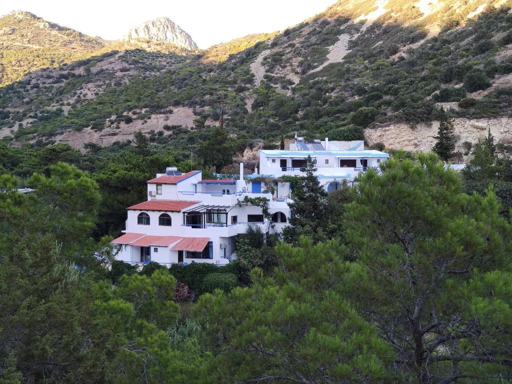 a large white house on a hill with trees at Oleander's Garden Traditional Cretan Cottage in Ferma