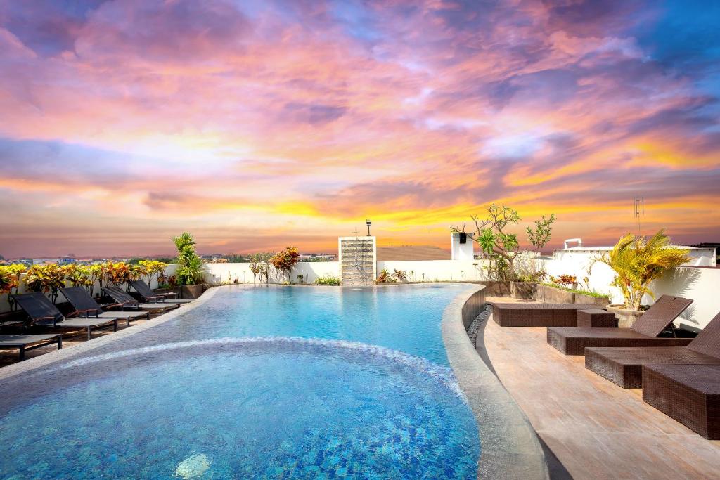 una piscina con tumbonas y una puesta de sol en Nikhila Seminyak Bali en Seminyak