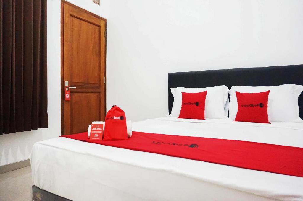 a bedroom with a bed with red pillows at RedDoorz @ Jalan Danau Limboto in Malang
