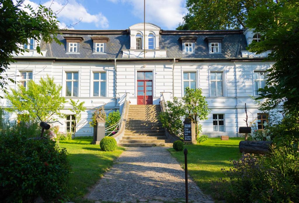 uma grande casa branca com uma porta vermelha em Gut Boltenhof em Fürstenberg-Havel