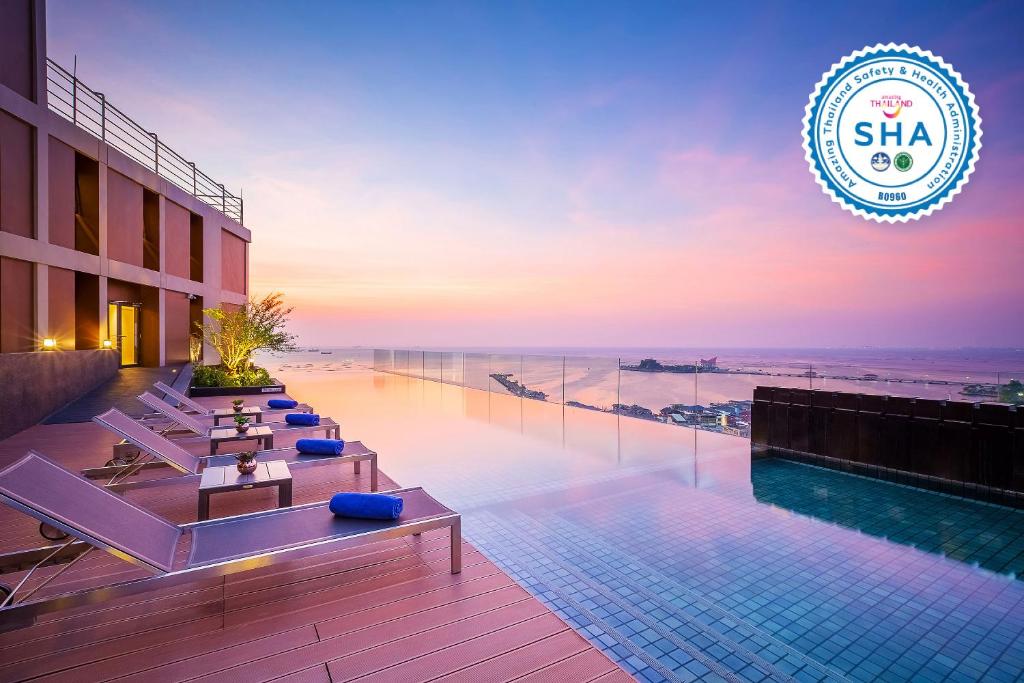 a hotel with a swimming pool with a view of the ocean at Somerset Harbourview Sri Racha - SHA Extra Plus in Si Racha