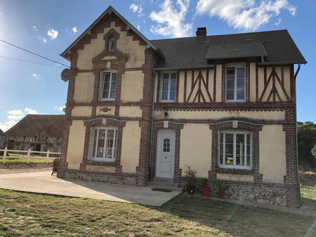 een oud bakstenen huis met een witte deur bij Haras Cour Lozey in Sainte-Marguerite-des-Loges