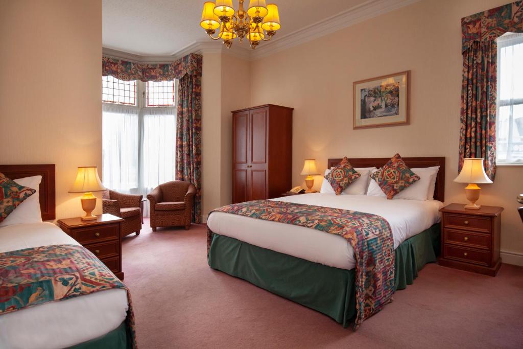 a hotel room with two beds and a chandelier at Ashley Hotel in Cambridge