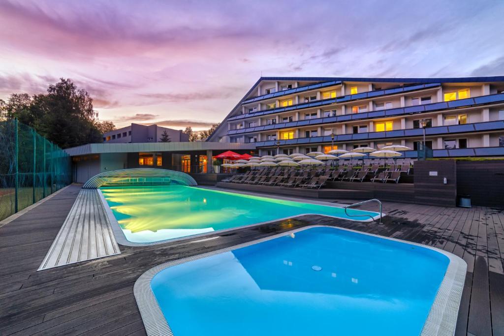 a hotel with a swimming pool on a deck at Hotel Jezerka in Seč