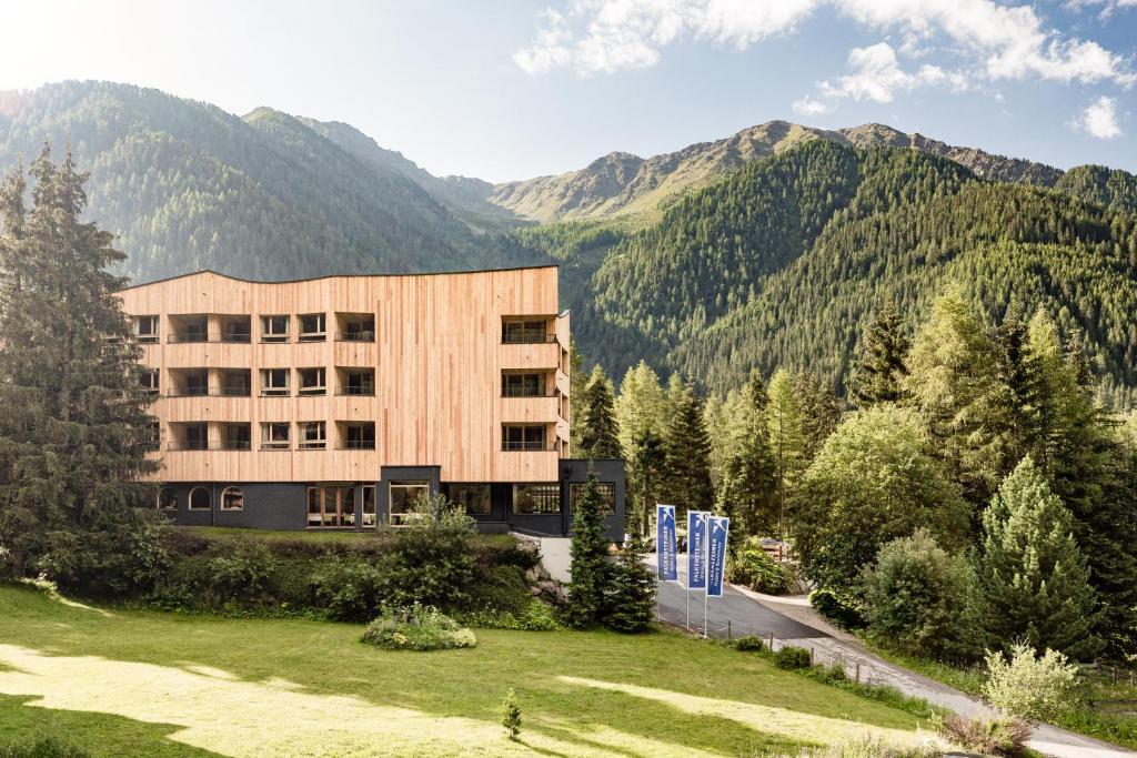 un edificio con montagne sullo sfondo di Falkensteiner Hotel Antholz - Adults only a Anterselva di Mezzo