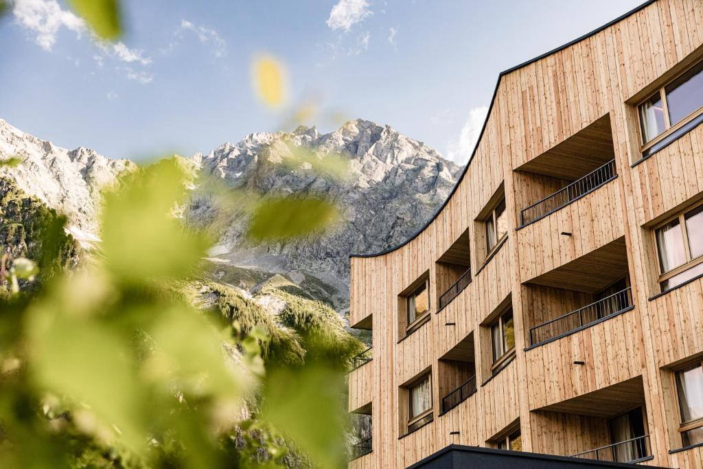 a building with a mountain in the background at Falkensteiner Hotel Antholz - Adults only in Anterselva di Mezzo