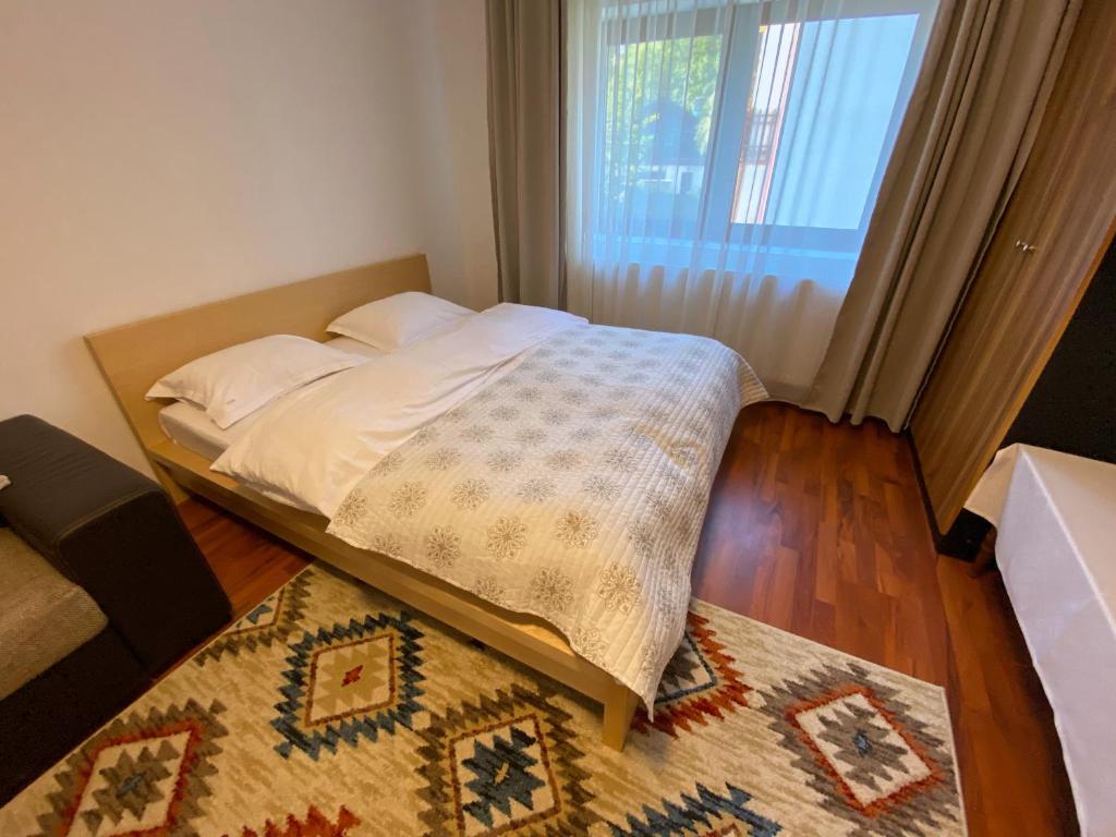 a bed in a room with a window and a rug at Apartament Viva Predeal in Predeal