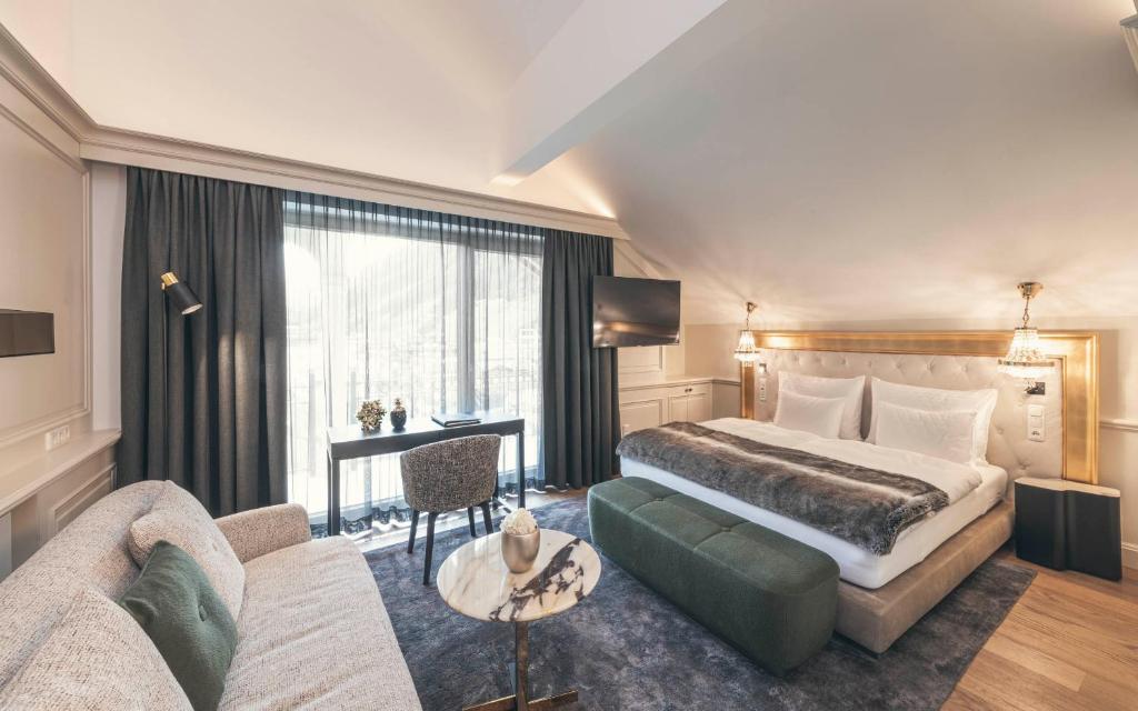 um quarto de hotel com uma cama e um sofá em Schlosshotel Ischgl 5-Sterne Superior em Ischgl