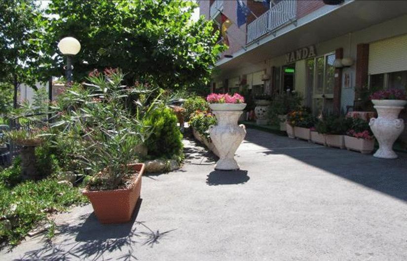 two large white vases with flowers inront of a building at Hotel Nanda in Chianciano Terme