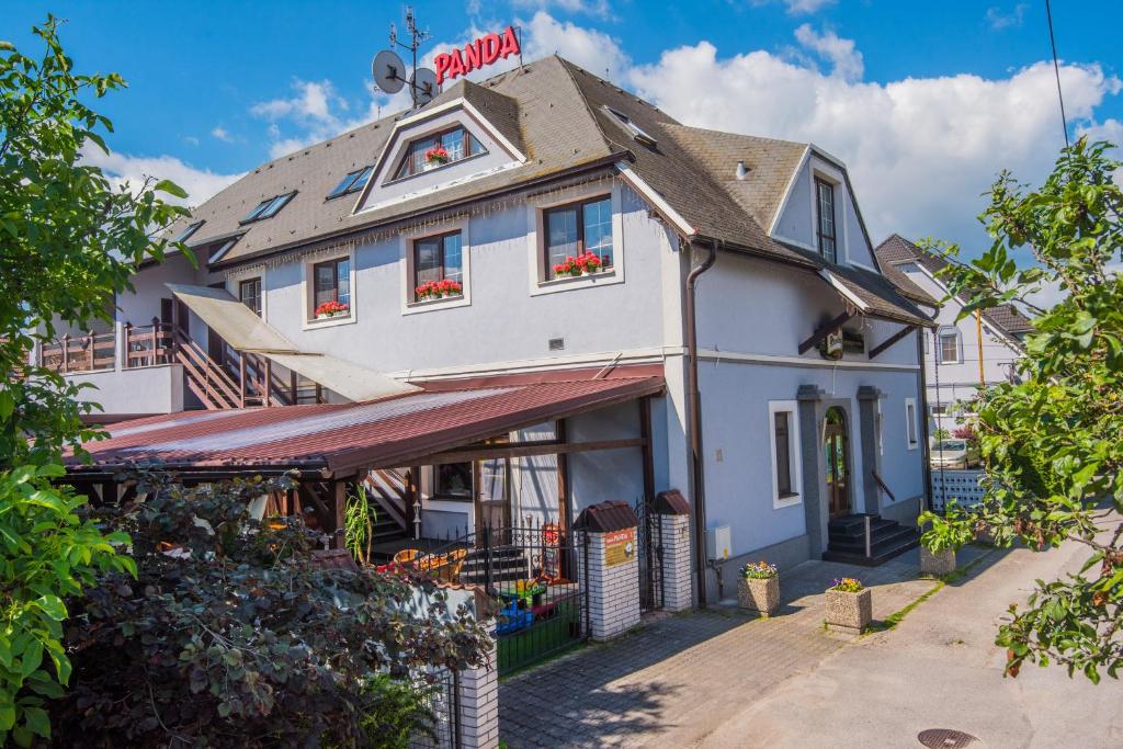 a white building with a red sign on top at Penzion PANDA Tourist in Turčianske Teplice