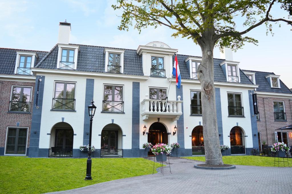 ein großes weißes Haus mit einem Baum davor in der Unterkunft Fletcher Strandhotel Haamstede in Burgh Haamstede