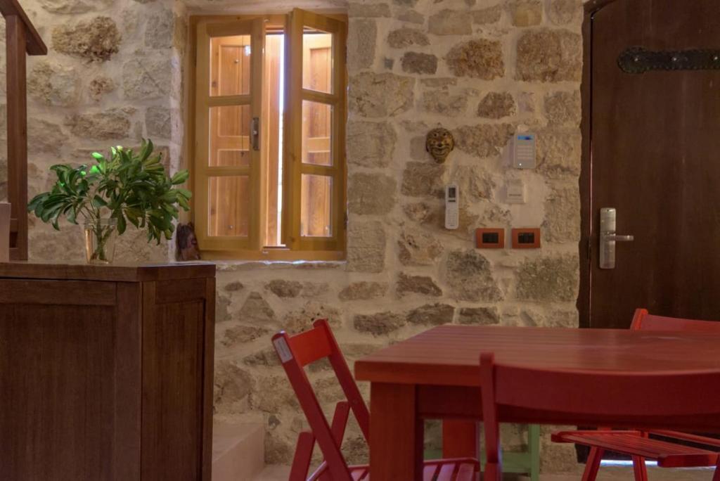 a dining room with a table and a stone wall at Roots Dhermi in Dhërmi