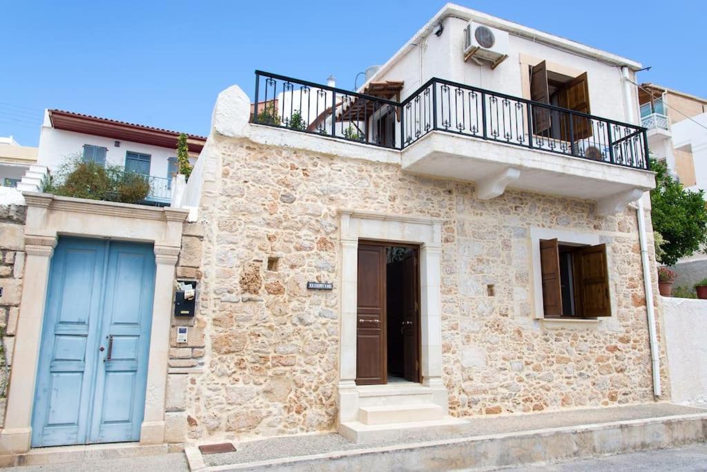 uma casa de pedra com uma porta azul e uma varanda em Traditional House under Kazarma Fortress in Sitia em Sitia