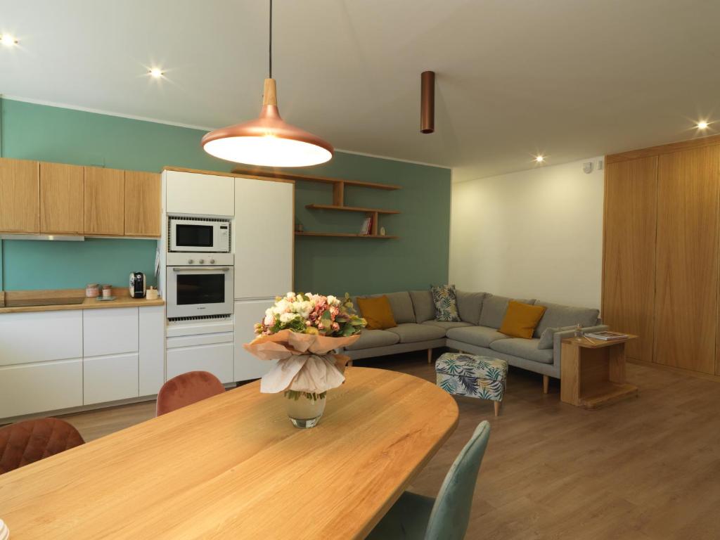 a kitchen and a living room with a table with flowers on it at L'Atelier du Temps - Elvimo Apartment in Aosta