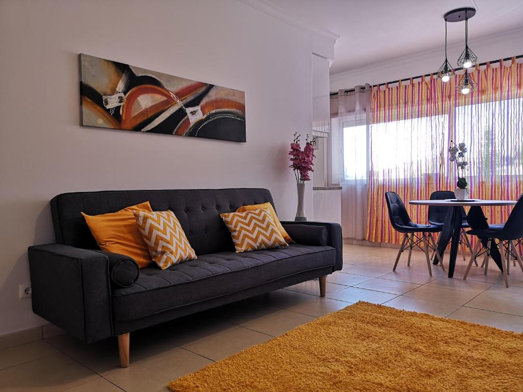 ein Wohnzimmer mit einem schwarzen Sofa und einem Tisch in der Unterkunft Armação de Pêra Praia Mar Sol in Armação de Pêra