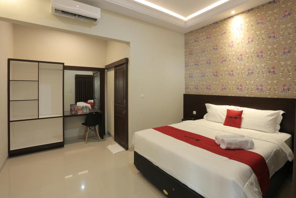 a bedroom with a large bed with a red blanket at RedDoorz Plus near Solo Paragon Mall in Bonorejo