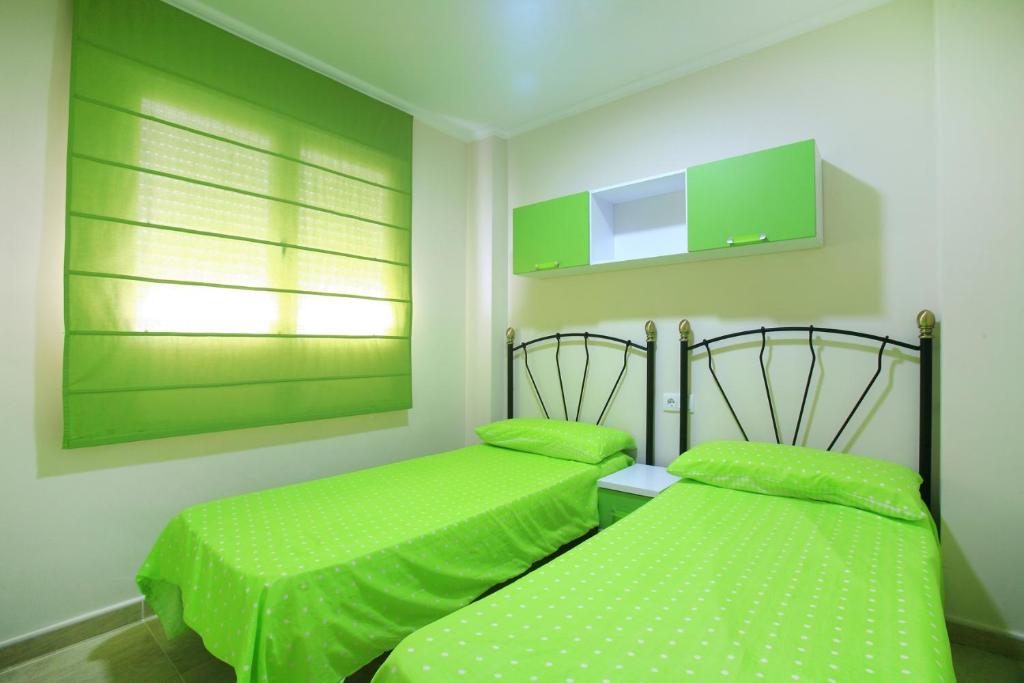 2 Betten in einem Zimmer mit grüner Bettwäsche in der Unterkunft Apartamentos en la playa Edimar II in Gandía