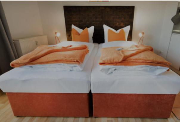 Duas camas com almofadas cor-de-laranja por cima. em H&H Apartments im Herzen der Stadt super zentral ruhig mit Kochnischen Balkon oder Empore em Greifswald