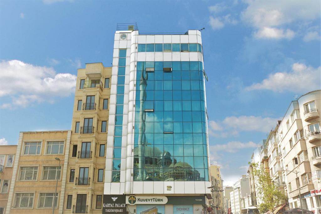 un edificio alto de cristal en una calle de la ciudad en Kartal Palace Taksim Square FAMİLY HOTEL, en Estambul