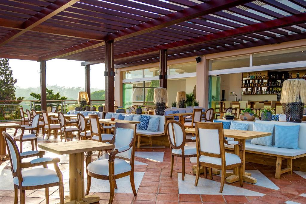 a restaurant with wooden tables and chairs and windows at Grande Real Santa Eulalia Resort & Hotel Spa in Albufeira