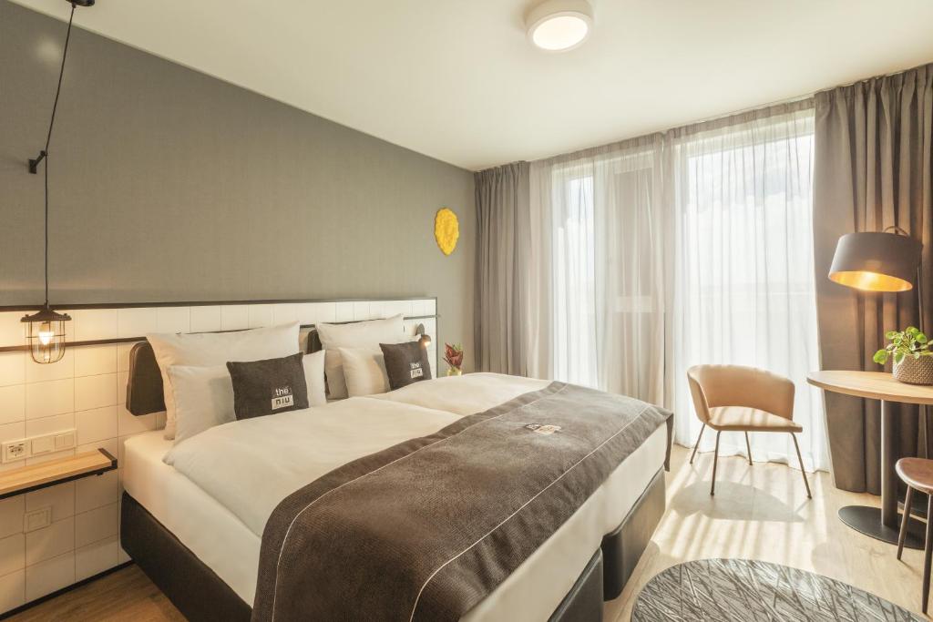 ein Hotelzimmer mit einem großen Bett und einem Tisch in der Unterkunft the niu Leo in Nürnberg