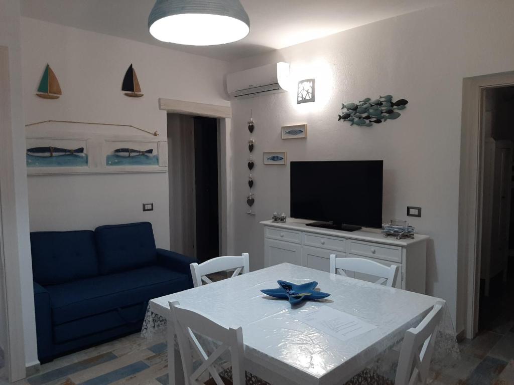 uma sala de estar com uma mesa branca e um sofá azul em Appartamento Residence Mirice Vignola mare Aglientu casa Giorgia em Aglientu