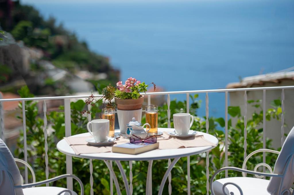 una mesa blanca con bebidas y una planta en el balcón en Casa Bellina, en Positano