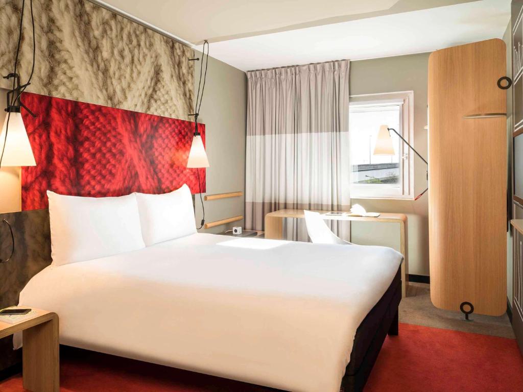 ein Hotelzimmer mit einem großen weißen Bett mit einer Flagge darauf in der Unterkunft ibis Paris Saint-Denis Stade Sud in Saint-Denis