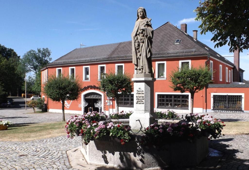 uma estátua de uma mulher em frente a um edifício vermelho em Hotel Weisses Ross em Konnersreuth