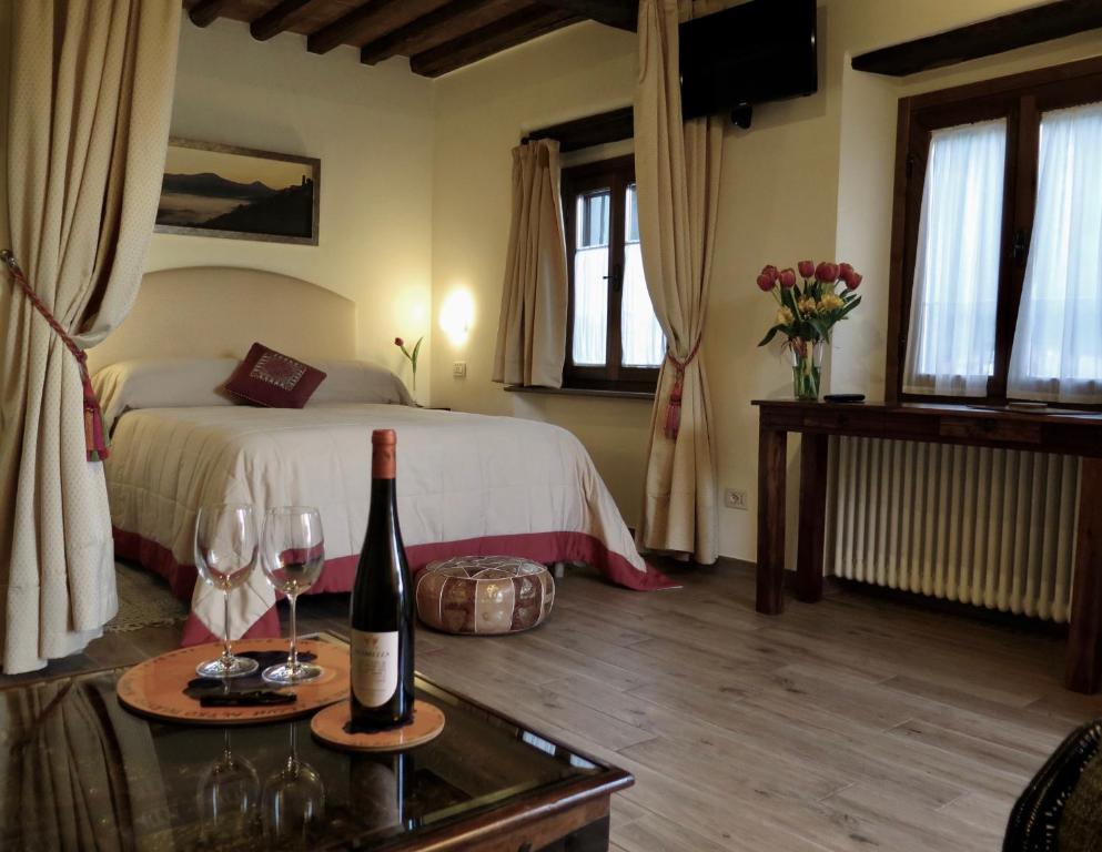 een slaapkamer met een bed met een fles wijn en glazen bij Andante appartamenti in Castelnuovo di Val di Cecina