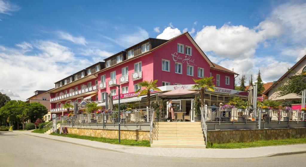czerwony budynek z restauracją przed nim w obiekcie Eden Hotel w mieście Bad Krozingen