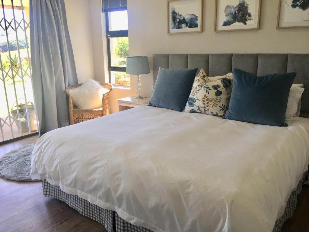 1 dormitorio con 1 cama blanca grande con almohadas azules en C’est La Vie, en Balgowan