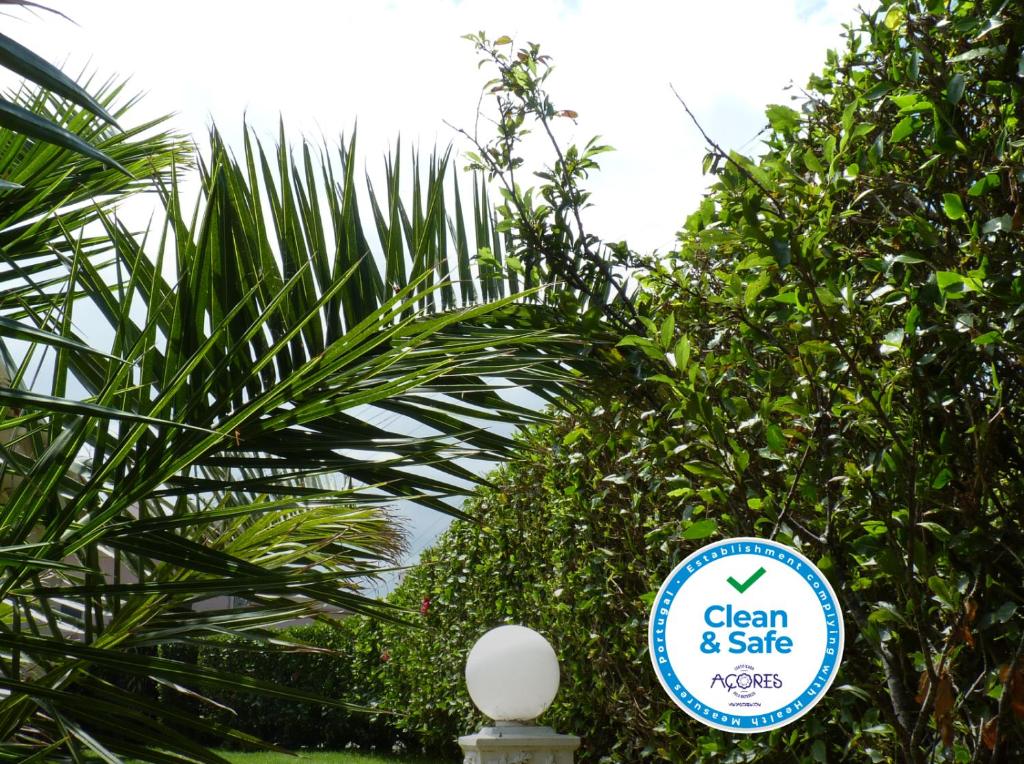 a sign that says clean and safe in front of trees at AZORES GARDEN HOUSE - Private Suites & Apartments - Automatic Self Check-in in Ponta Delgada