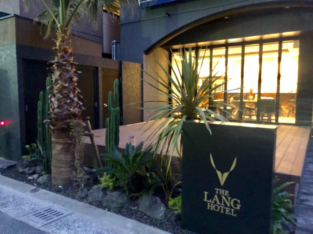 a sign in front of a building with plants at THE LANG HOTEL Hakata in Fukuoka