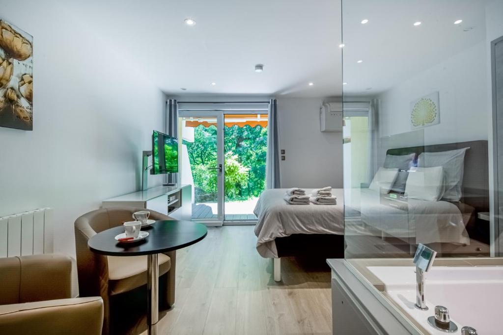 1 dormitorio con cama, mesa y bañera en Wellholidays 19 - studio balnéo et terrasse piscine, en Boersch