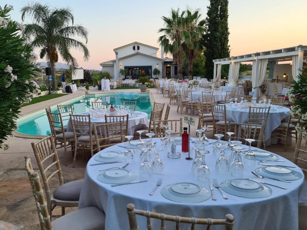 a dining room table with chairs and umbrellas at Villa Vravrona Tower & Suites in Markopoulo