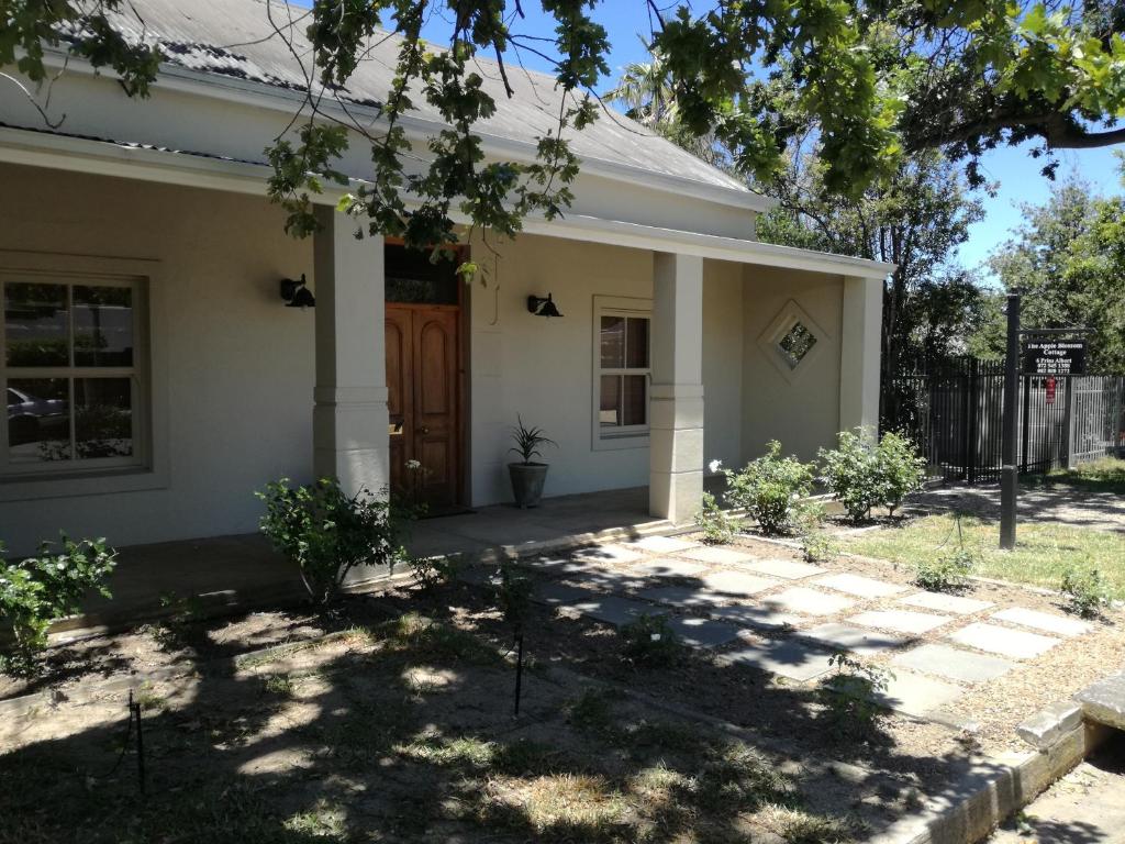 a small white house with a wooden door at The Apple Blossom Cottage in Villiersdorp