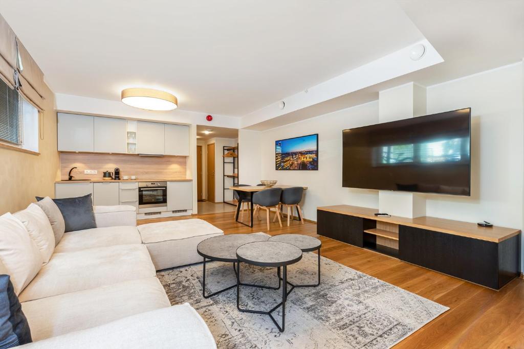 a living room with a white couch and a flat screen tv at Gustav Apartments - City Center Comfort in Tartu