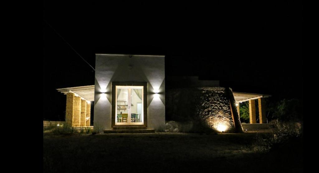 une maison avec des lumières à l'avant de celle-ci la nuit dans l'établissement Trullomio, à Torre Suda
