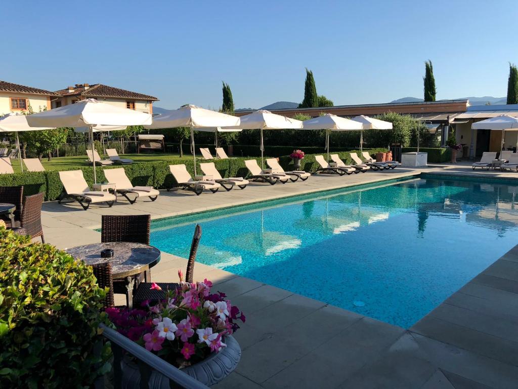 a swimming pool with chairs and tables and umbrellas at Villa Olmi Firenze in Florence