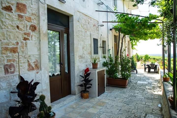 eine Terrasse mit Topfpflanzen und ein Gebäude mit einer Tür in der Unterkunft Belvedere in Locorotondo