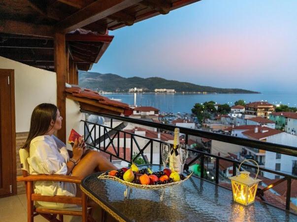 a woman sitting on a balcony with a bowl of fruit at Anna Maria Apartments Views in Neos Marmaras