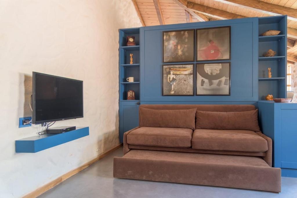a living room with a couch and a tv at Roots Dhermi in Dhërmi