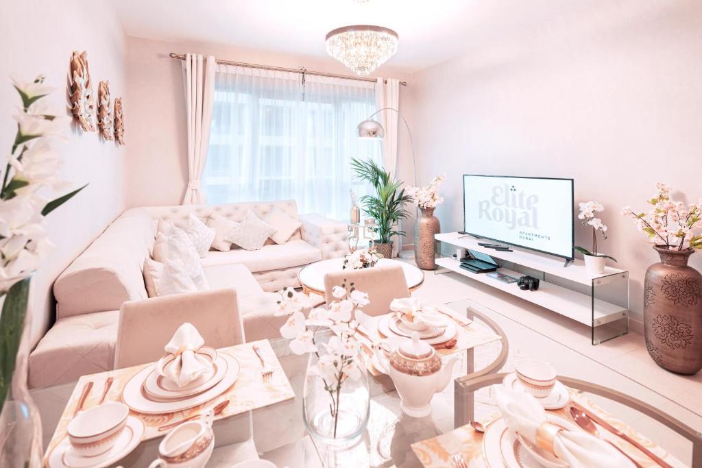 a living room with a white couch and a tv at Elite Royal Apartment - Onyx in Dubai