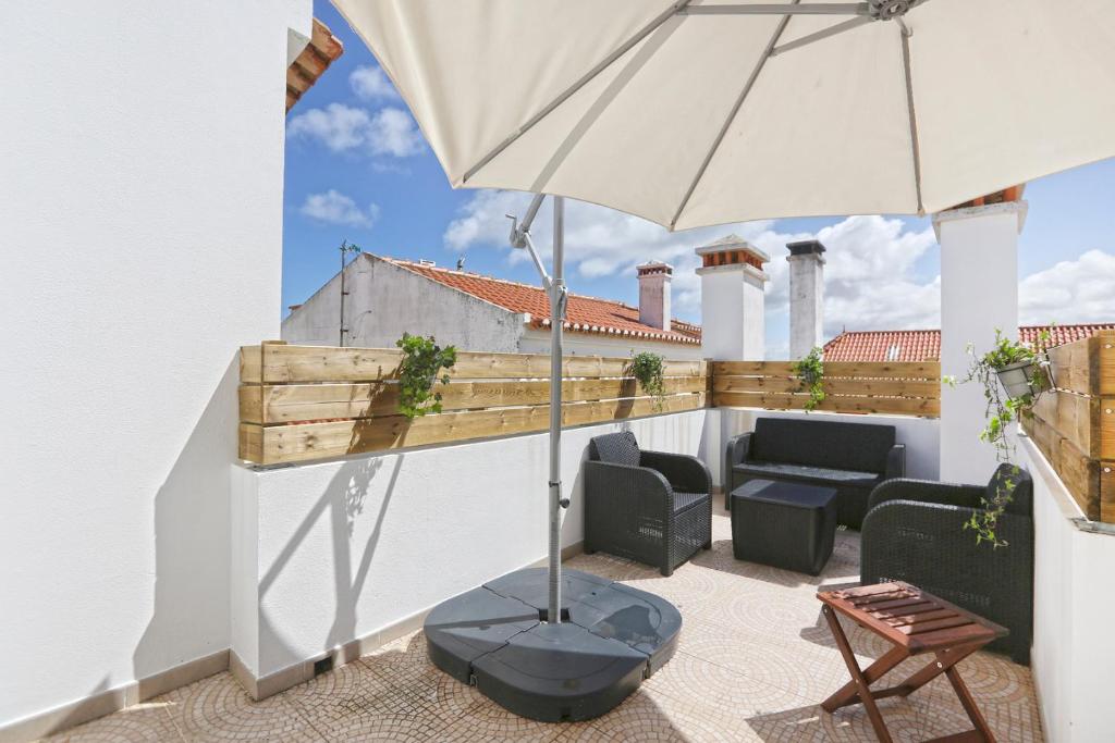 a patio with a table and an umbrella at Sunrise Terrace Peniche in Peniche