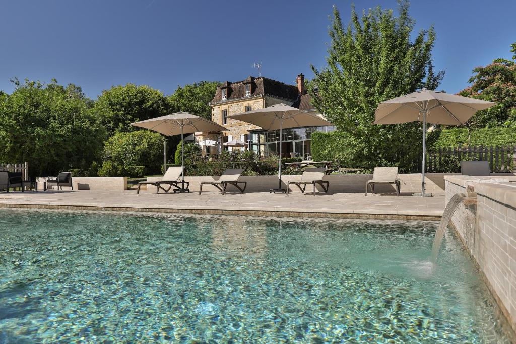a swimming pool with chairs and umbrellas at Hotel Restaurant La Verperie in Sarlat-la-Canéda