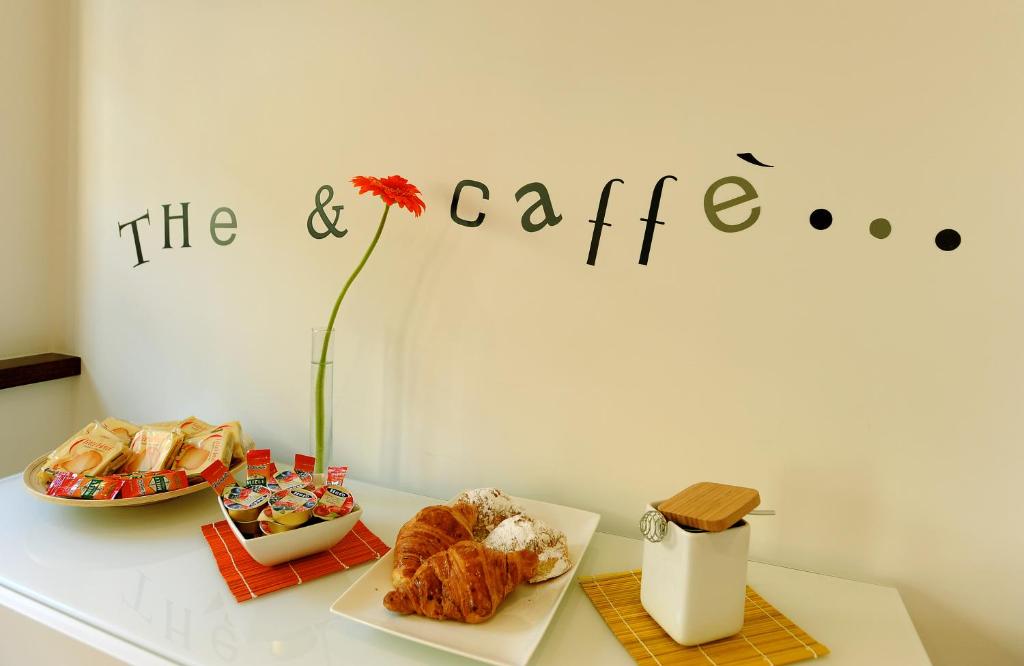 a table with pastries and a flower on a wall at Honey Rooms in Rome